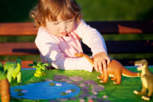 Toddler kid playing with a toy dinosaur.